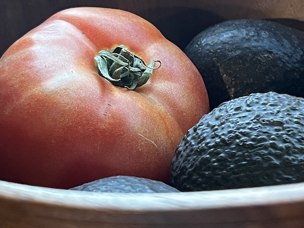 A tomato and avocados in a bowl