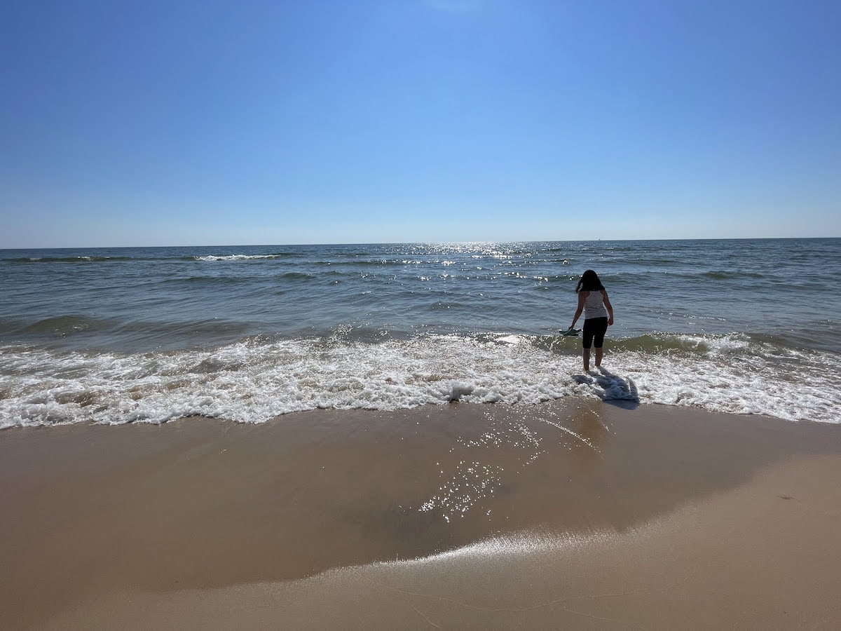 The sandy beach on lake Michigan with my daughter dipping her toes in the water