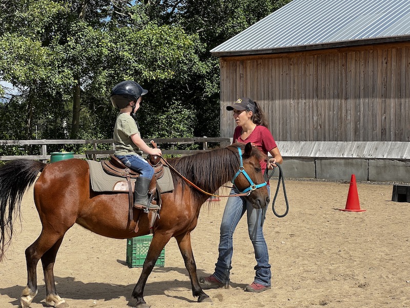 Our son riding a the small horse named Chocolatin at horse camp with an instructor