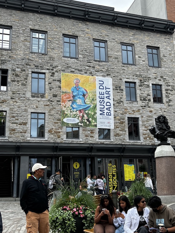 A sign in old Quebec City, inviting people to view the Museum of Bad Art