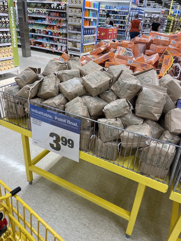 A pile of my wife's coveted brand of canadian buckwheat flour in a huge pile for sale with little fan fair